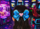 Person with a blue hair bow in an arcade setting with colorful lights and games.