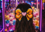 Person with a colorful hair bow in front of a claw machine filled with toys.