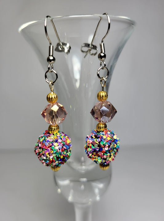 Introducing our exquisite Dazzle Dangle Earrings – a captivating blend of elegance and vibrancy that will elevate your style to new heights. These eye-catching earrings feature a stunning statement bead, meticulously adorned with a dazzling array of sparkling colors that catch the light with every movement.