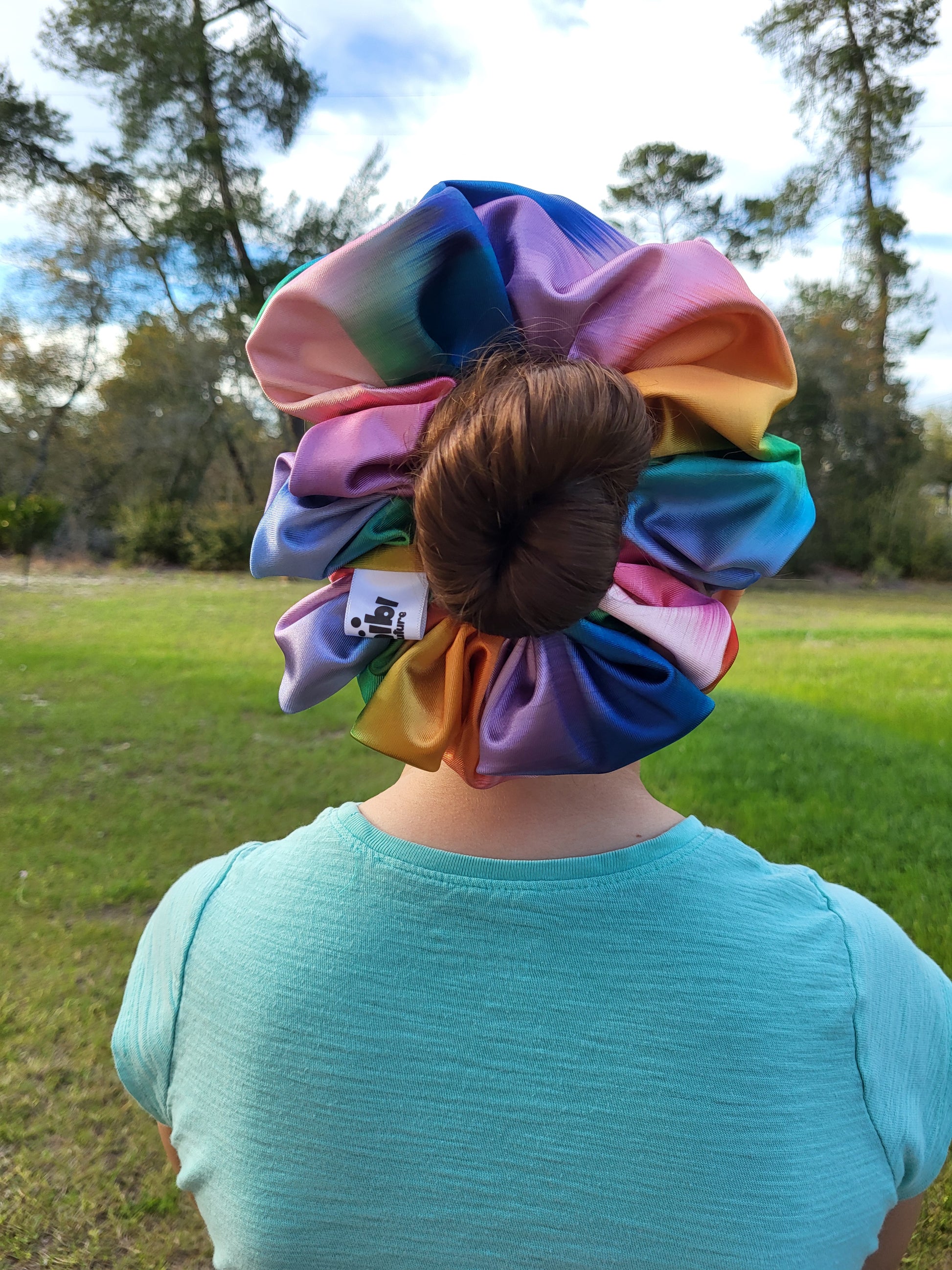 Introducing the Evangeline Chibi XXL Oversize Scrunchie, a vibrant accessory designed to make a bold statement. This oversized scrunchie features a stunning blend of rainbow colors, adding a playful and energetic touch to your hairstyle.