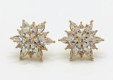 Pair of gold and crystal flower-shaped earrings on a black background