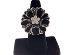 Black flower-shaped earring on a black stand against a white background