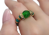 Green gemstone ring on a hand with a white background