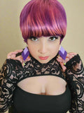 Person with vibrant purple hair wearing a black lace top.