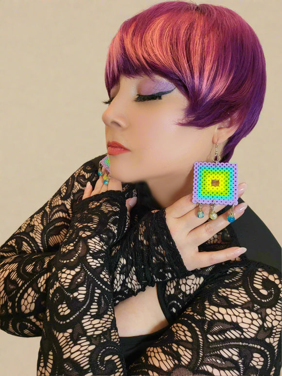 Person with colorful hair wearing a black lace top and colorful earrings.