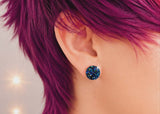 Person with vibrant purple hair wearing a blue earring.