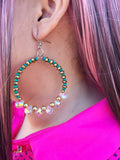 Close-up of a colorful beaded earring worn by a person with pink hair.
