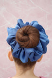 a backview of a blue scrunchie around a young girls bun