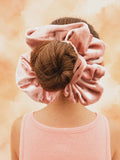 Person wearing pink scrunchies on a soft peach background