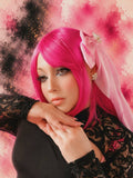 Person with bright pink hair and a veil against a colorful abstract background
