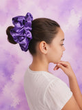 Person with a purple scrunchie in their hair against a purple background