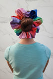 a back view of a young child wearing an oversize colorful scrunchie around her bun