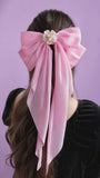 Pink hair bow with a flower on a purple background
