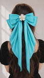 Turquoise hair bow with a white flower on a plain background