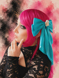 Person with pink hair and a blue bow against a colorful abstract background