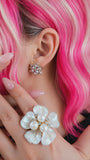 Close-up of woman wearing the Starlight Empress Studs on her  ear with a floral earring, pink hair, and a floral ring.