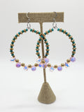 two beaded hoop earrings hanging on earring display