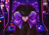 Person with a large, decorative hair bow in front of an arcade machine