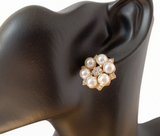 a closeup of a faux pearl cluster earrings with rhinestones and gold accents