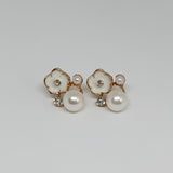 a close up of faux pearl earrings with gold accents and rhinestones